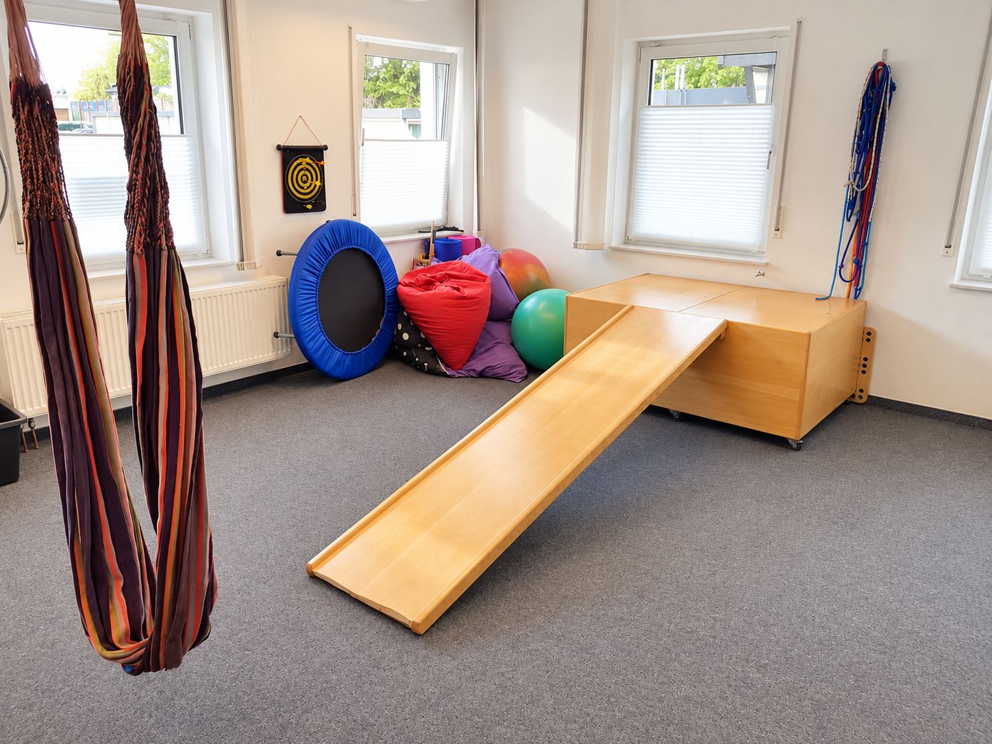 Therapieraum der Praxis mit Hängeschaukel, Rutsche und Trampolin